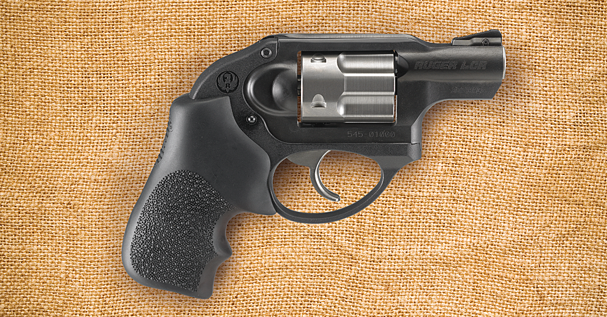 A hammerless black Ruger LCR snub-nosed .357 Magnum revolver lying on a burlap background.