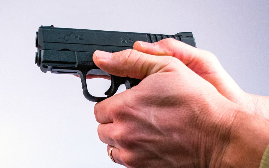 Photo of proper two-handed grip on a black Springfield Armory XD-S 9. Both of the shooter's thumbs run parallel with the slide, tucked closely together.