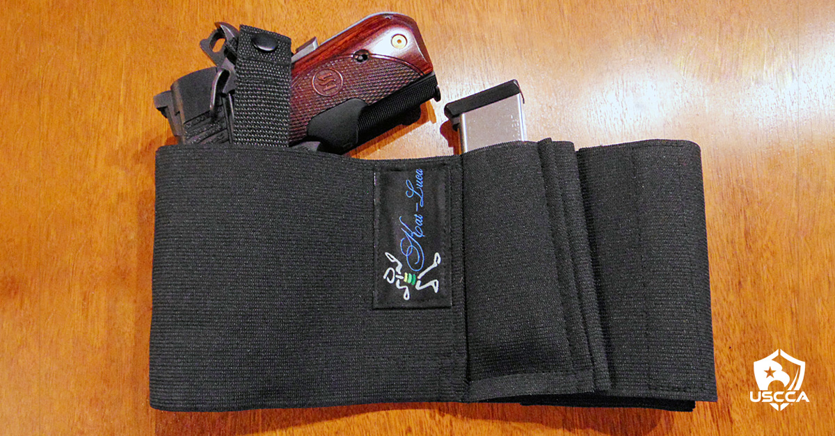 The Crimson Trace Green Lasergrips on a Remington R1 Executive Ultralight 1911 peeks out of the top of a Kat-Luca belly band holster along with a spare magazine.